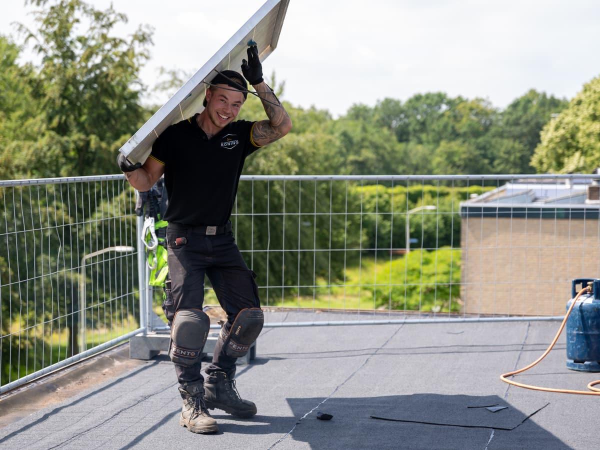 Vakman met zonnepaneel op een plat dak